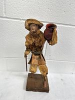 Front angle photo showing full figure on wooden base, details of clothing and posture.