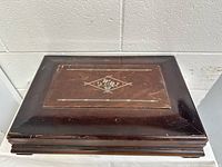 Top and side view of the closed wooden cutlery storage case showing the decorative inlaid design and wear.