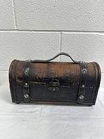 Front view of vintage wooden curved-top wine case with leather straps and metal latch.