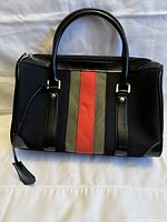 Front view of black handbag with red and gray vertical stripes and two black handles