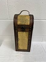 Front view of the wooden wine bottle case showing the leatherette map trimmed front panel and metal clasp.