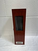 Front view of closed wooden gift box with BDO metal plaque and window showing foam inside.