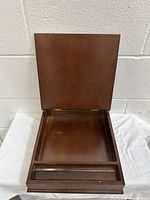 Open wooden pencil case showing interior compartment and small organizer space