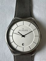 Close-up of watch face showing Skagen branding, minimalist dial, and date window.