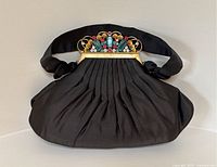 Front view of black satin evening bag with pleated body and jeweled gold-tone frame