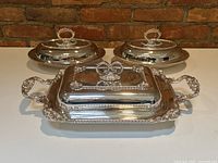 All three silver-plated covered dishes: rectangular platter center, two oval dishes behind.