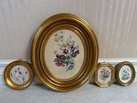 Group photo of four framed floral paintings including one large oval, one smaller oval, one small circular, and one small octagonal on silk.