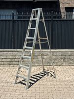Full view of the 8 foot aluminum A-frame ladder standing on outdoor pavement, showing its overall shape and size.