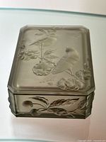 Top view of smoky satin crystal lidded box showing engraved birds and floral patterns.