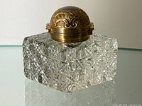 Front view of the cut crystal inkwell showing the detailed engraving on the gold plated domed lid and the intricate cut crystal pattern on the square base.