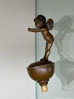 Side view of bronze cherub call button showing detailed figure and switch mechanism at the bottom.