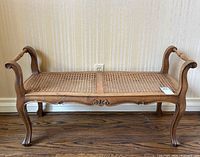 Full front view of bench showing carved apron and caned seat