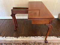 One half of tabletop opened, revealing green baize interior and sliding compartment