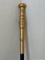 Full view of gilt handle atop ebony shaft