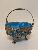 Frontal view of bowl showing blue glass insert and bronze-tone grapevine metal frame