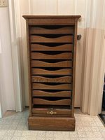 Front view of oak cabinet showing tambour roll-front door closed and ten drawer fronts.