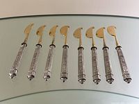 Full set of eight citrus peelers side by side on glass surface