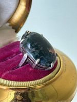 Front view of ring in open gold and velvet box highlighting the oval moss agate stone and six-prong setting.
