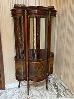 Full front view of the ornate wooden display cabinet with curved glass panels and gilt metal trim.