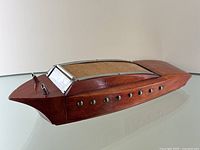 Side view of wooden boat humidor showing figural hull shape, wood grain, metal rivets and smokestacks