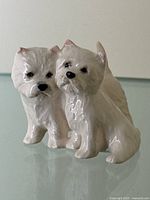Front view of the glazed ceramic figurine showing two West Highland White Terriers together, detailing on fur and facial features visible.