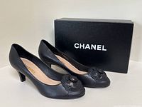 Both pumps positioned front-left of Chanel-branded box