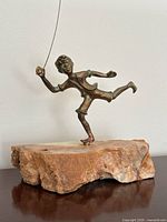 Front view of bronze boy figurine and marble base showing mid-stride pose and kite wire