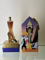 Perfume bottle standing on original box alongside the colorful art deco box packaging.