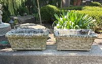 Front view of both planters side by side on a concrete ledge with garden background