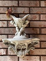 Overall view of cement wall sconce bracket with cherub planter mounted on brick background