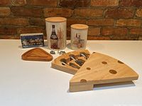 Front view of entire lot showing wooden cheese board with knives, decorative jars, metal bottle openers, and wooden tray