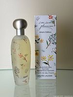 Perfume bottle and matching box with floral design shown side by side.