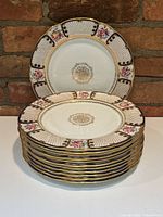 Two plates displayed: one upright showing full border pattern, one atop a stack to show set quantity.