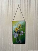 Full view of hanging floral glass art panel against wallpaper background.