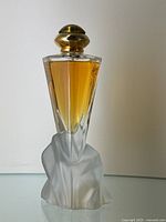 Full front view of the vintage perfume bottle showing the amber liquid in faceted clear glass and the frosted glass sculptural base.