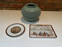 Korean celadon vase displayed with two Japanese decorative dishes (round and rectangular) on a flat surface.