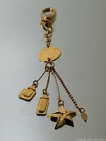 Photo of full gold plated Lalique perfume charm keychain showing four hanging charms including perfume bottle shapes and a flower charm.