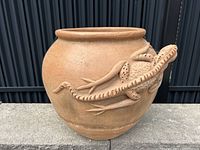 Front view of terracotta planter showing iguana relief