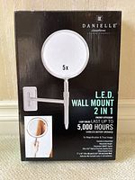 Front view of unopened box displaying the product image, specifications, and features such as 5x magnification, 5000 hour LED life, battery operated and cordless function.