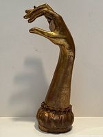 Front right side view of gilt resin hand sculpture showing overall shape and finish.