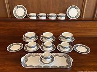 Overview of entire set: cups, saucers, plates, mugs and tray arranged on wooden surface