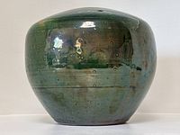 Front view of the rounded art pottery vase showing the green iridescent glaze with circular indentation pattern.