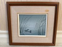 Framed painting of two loons on water surrounded by reeds, showing the full artwork, linen mat with stain, and wooden frame with minor damage.