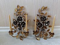 Pair of two-tone metal rose wall sconces with gold leaves and silver roses, with candles inserted. One leaf detached on floor.