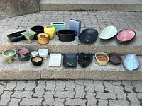 Photo showing a large assortment of planters and pottery pieces on stone steps, displaying different colors, sizes, and shapes.