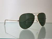 Side angled view showing gold-tone metal frame, slim temples, and green lenses