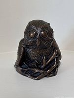 Front view of the signed bronzed owl sculpture showing detailed feathers and branch base.