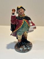 Front view showing the detailed face, attire, and bell in right hand, scroll in left hand.