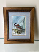 Miniature framed painting of a chickadee in wooden frame with decorative edge.