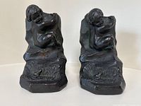 Front view of the pair of bronze bookends showing cherub with frog at base.